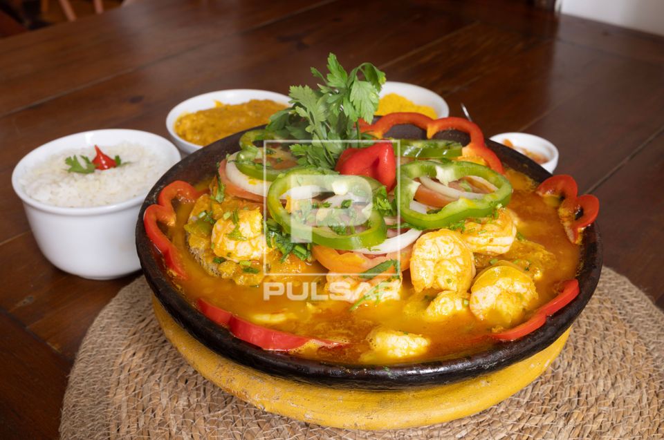 Moqueca de camarão e acompanhamentos servida em restaurante