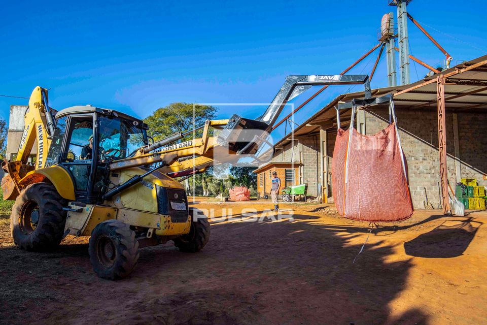 Trator com sistema hidráulico movimentando sacas com 500 kg de nozes-pecã recém colhidas