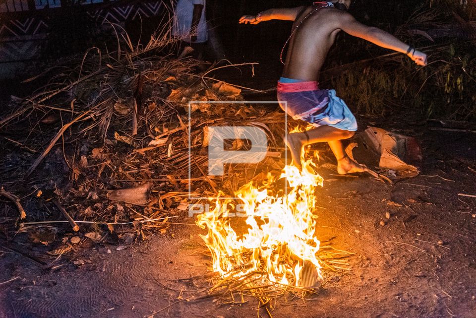Menino indígena Goitacá - autodeclarado ou de retomada pulando fogueira na aldeia urbana multiétnica Maraca