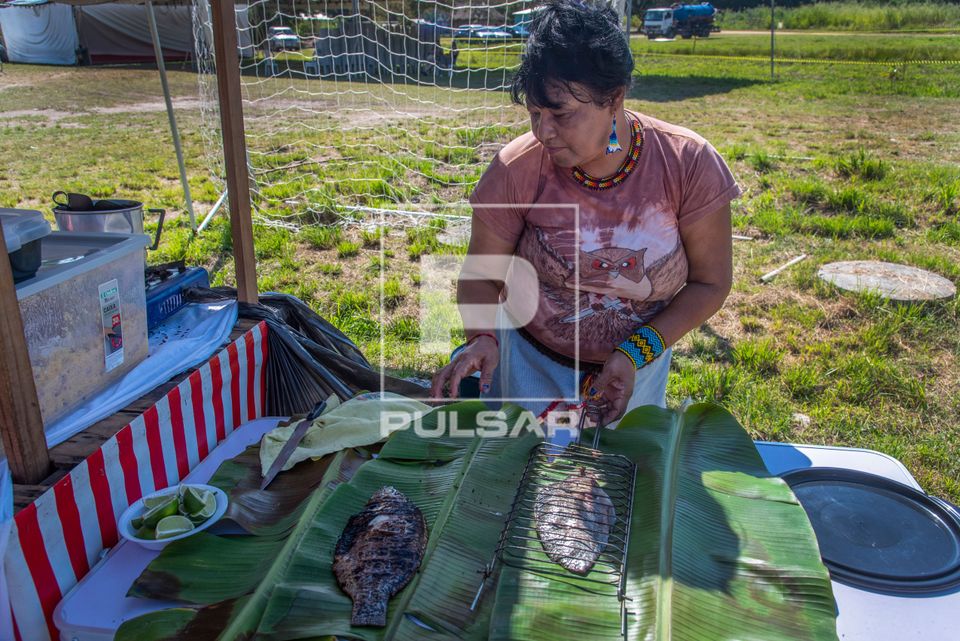 Indígena da etnia Guarani prepara peixe na brasa para venda durante o evento Maricá Indígena 2026 na Aldeia