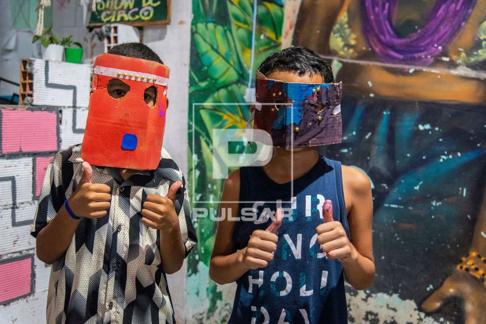 Crianças da Comunidade do Complexo do Alemão posando com máscaras feitas durante oficina ministrada por Jul