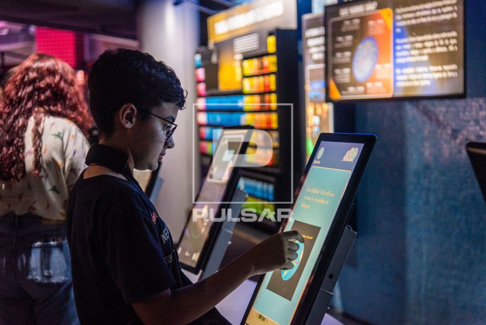 Menino interagindo com painel digital no Museu do Universo no Planetário do Rio