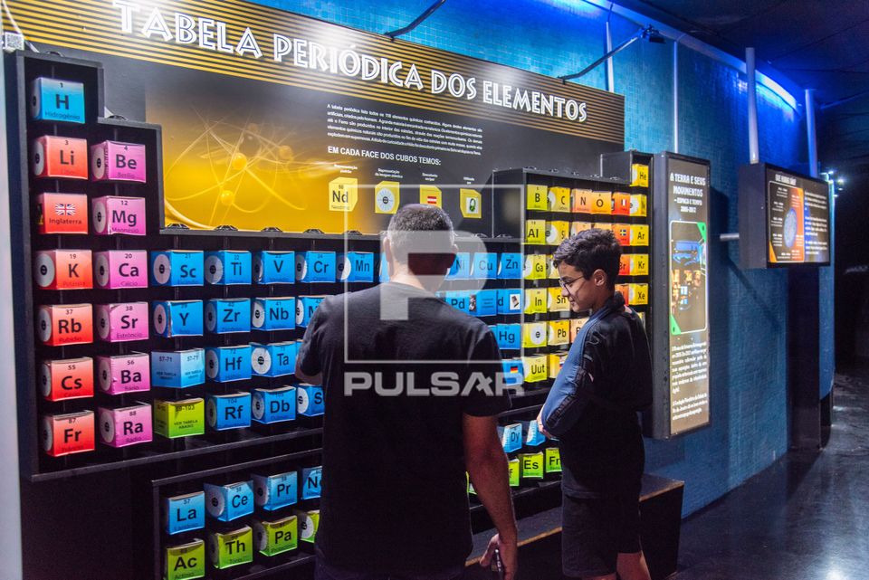 Pai e filho interagem com tabela periódica dos elementos no Museu do Universo no Planetário do Rio