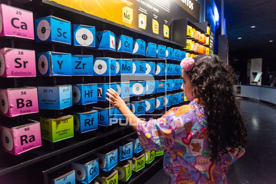 Menina interagindo com tabela periódica dos elementos no Museu do Universo no Planetário do Rio