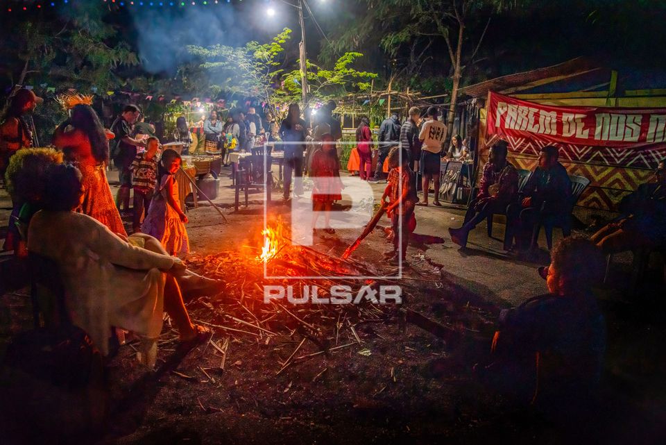 Pessoas se aquecem na fogueira durante festa junina na aldeia urbana multiétnica Maracanã ou Marakanã