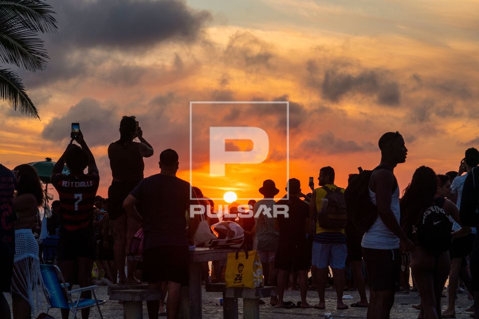Pessoas apreciando o pôr do sol na Praia do Arpoador