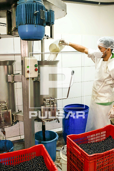 Trabalhador abastecendo com água despolpadeira de produção de polpa de açaí