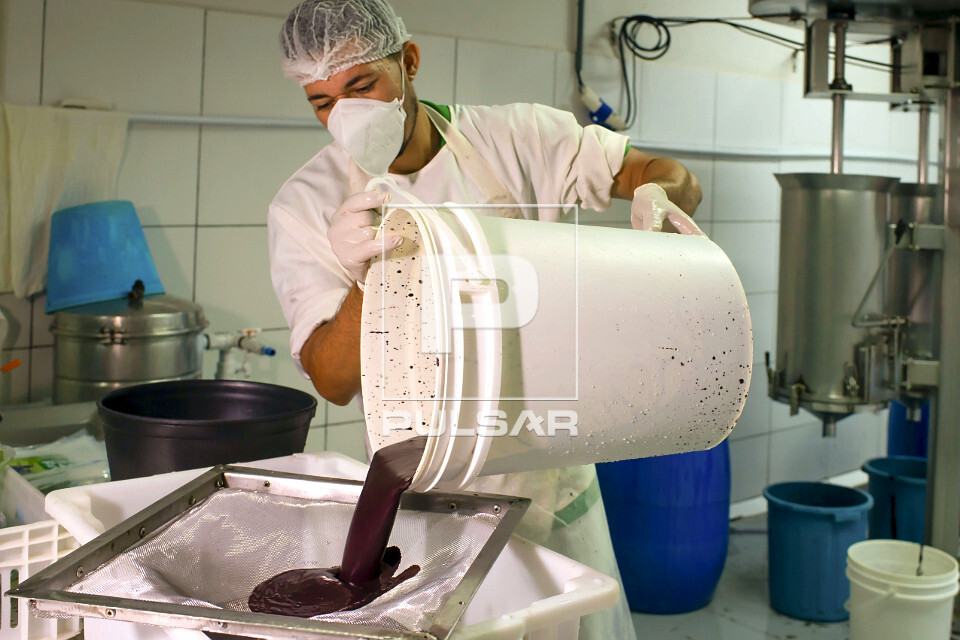 Trabalhador peneirando polpa de açaí
