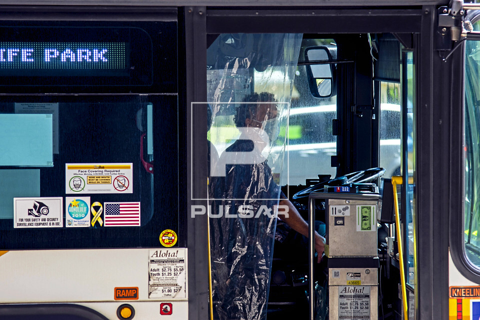 Detalhe de motorista de ônibus protegido por cortina de plástico e máscara durante pandemia do coronavírus