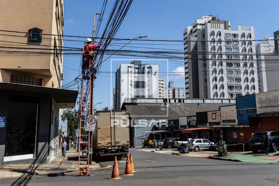 Trabalhador em poste realizando manutenção no cabeamento de internet - centro da cidade