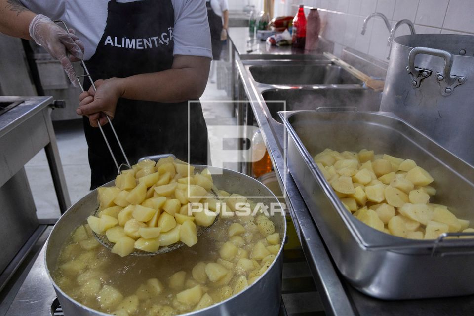 Cozinheira retirando batata cozida de panela em restaurante de preço popular 