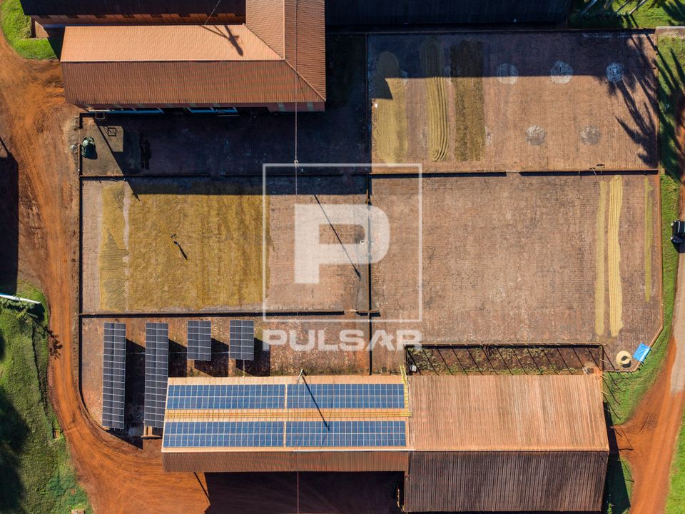 Vista de drone de terreiro de secagem de café e placa solares de captação de energia elétrica em fazenda