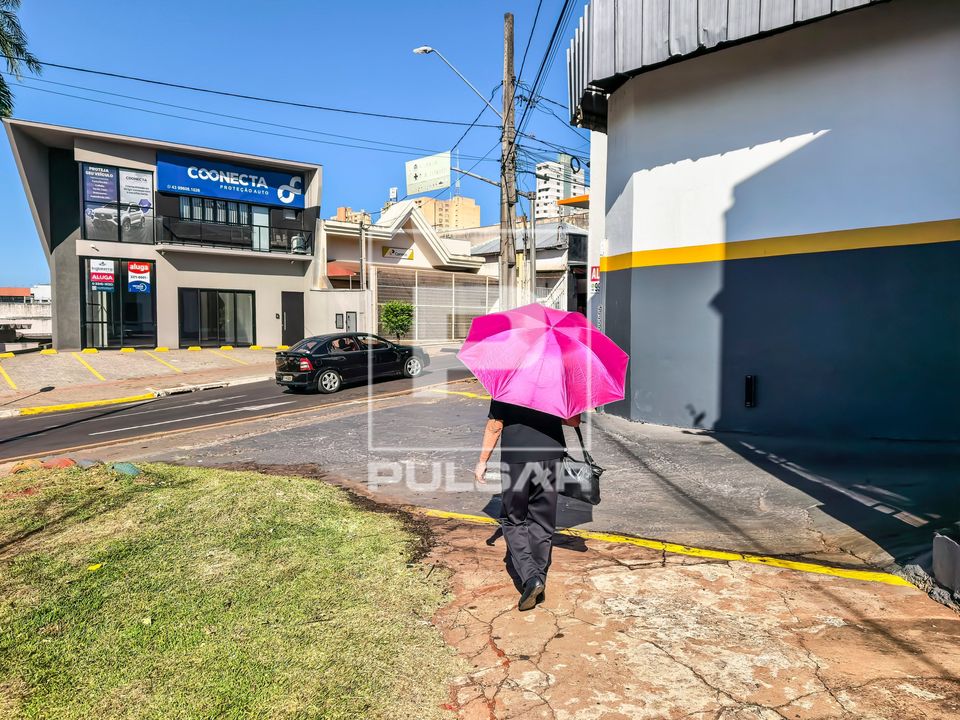 Pessoa caminhando com sombrinha para se proteger do sol no centro da cidade
