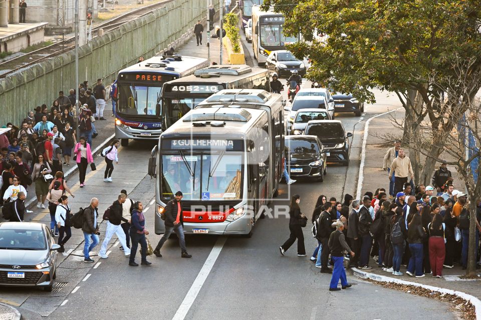 Passageiros atravessam avenida para tomar ônibus do PAESE na Estação Guaianases da Linha 11 Coral em dia de