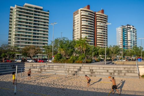 Pessoas jogando vôlei de areia na Praia da Ponta Negra - edifícios ao fundo