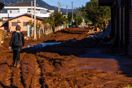 Moradora trafegando entre na lama deixada pelas enchentes no Vale do Taquari