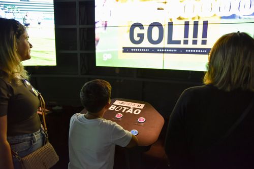 Pessoas na Sala da Dança do Futebol como se estivesse na sala de operações de uma TV no Museu do Futebol no