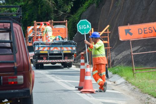 Trabalhador com placa de siga na Rodovia Bunjiro Nakao SP-250