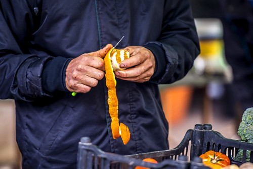 Consumidor descascando laranja orgânica à venda na Feira Ecológica Auxiliadora - 