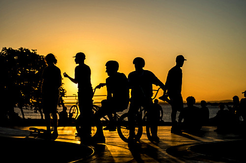Jovens em pista de skate com o pôr do sol na orla do Rio Guaíba - 