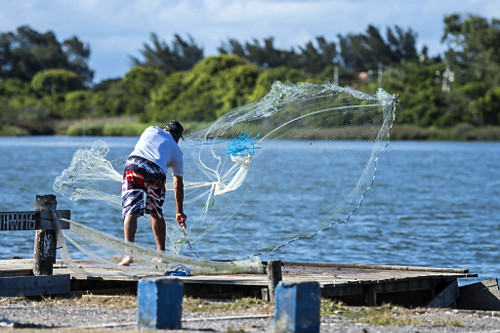 Pescador jogando tarrafa no estuário do rio Tramandaí
