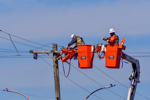 Trabalhadores fazendo reparo de rede elétrica após estragos causados por fortes ventos