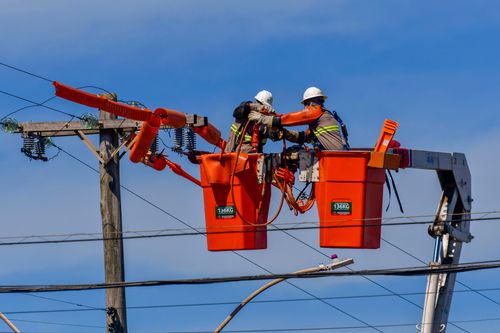 Trabalhadores fazendo reparo de rede elétrica após estragos causados por fortes ventos