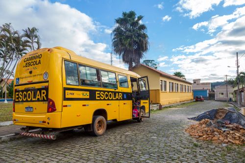 Alunos desembarcando de micro-ônibus de transporte escolar em frente à Escola Municipal Francisco Peixoto  