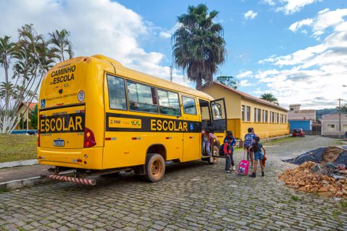Alunos desembarcando de micro-ônibus de transporte escolar em frente à Escola Municipal Francisco Peixoto  