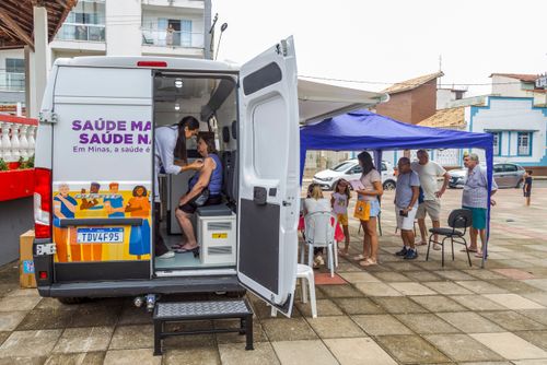 Enfermeira aplicando vacina em mulher durante campanha contra covid-19 e gripe dentro do vacimóvel na Praça 