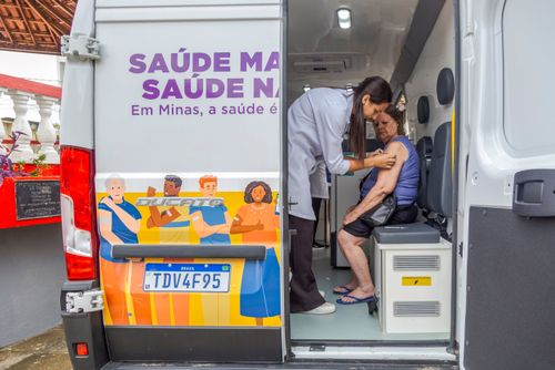 Enfermeira aplica injeção em mulher durante campanha contra covid e gripe dentro de veículo Vacimóvel na P