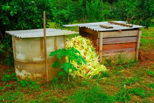 À esquerda recipiente com anel de concreto com composto orgânico - à direita recipiente feito com tábuas d