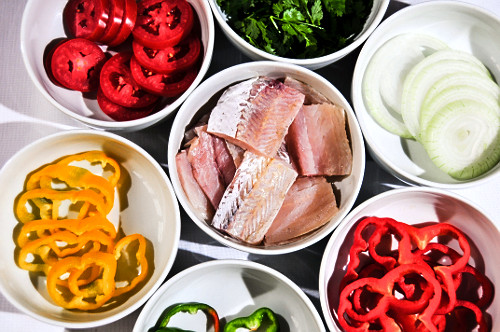 Ingredientes para moqueca de peixe, pimentões, cebola, peixe, tomate e coentro