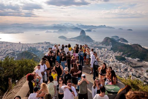Turistas no Cristo Redentor , Baía da Guanabara ao fundo e Complexo do Pão de Açúcar à direita