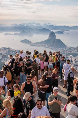 Turistas no Cristo Redentor , Baía da Guanabara ao fundo e Complexo do Pão de Açúcar à direita