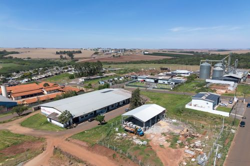 Vista de drone de galpões industriais , silos e área agrícola ao fundo