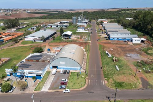 Vista de drone de galpões industriais , silos e área agrícola ao fundo