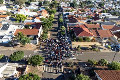 Vista de drone de procissão de Corpus Christi percorrendo rua de bairro residencial