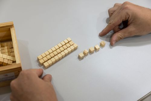 Compondo e decompondo números - estudante manipulando barras de dezena e cubinhos de unidade de material did�