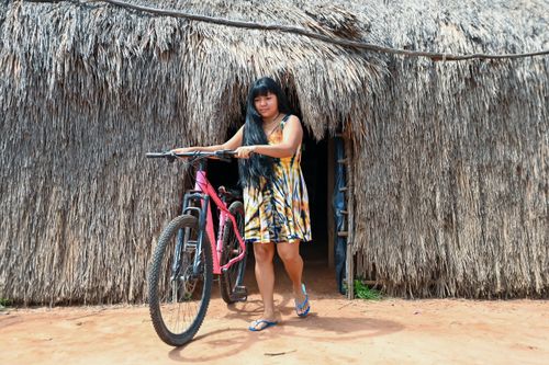 Indígena da etnia Wauja saindo da oca com bicicleta - Parque Indígena do Xingu