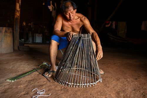 Indígena Waurá amarrando varetas em armadilha kuluto ou matapi de peixes em forma de cone - Parque Indígena