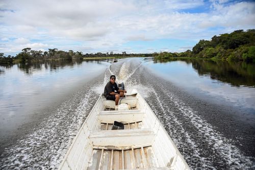 Jovem indígena Waurá pilotando voadeira a motor no Rio Tuatuari - Parque Indígena do Xingu
