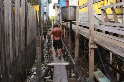 Pessoa caminhando em passarela suspensa em palafitas da comunidade Pico das águas no bairro São Geraldo