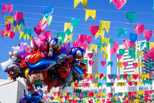 Venda de balões inflados com gás e bandeirolas decorando a Festa Junina no Memorial da América Latina