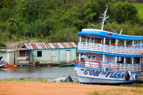 Casa flutuante na água e gaiola atracada em terra firme