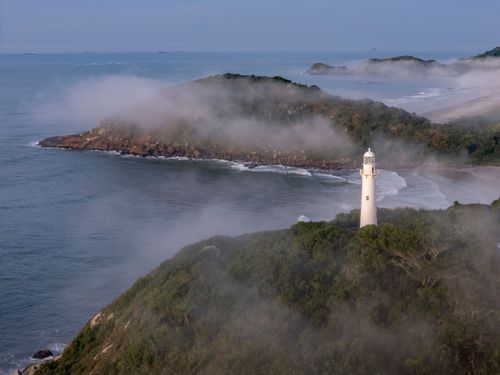 Nevoeiro ao amanhecer com Farol das Conchas sobre o Morro das Conchas no Parque Estadual da Ilha do Mel - Baí