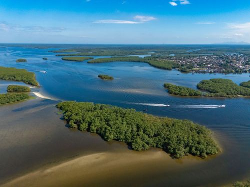 Vista de drone do rio Itiberê em trecho navegável - área urbana ao fundo - Baía de Paranaguá