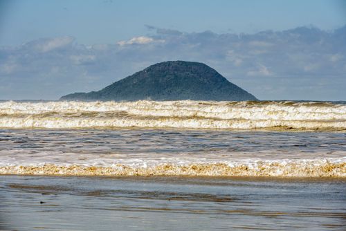 Ondas na praia de Guaratuba com ilha Montão de Trigo ao fundo