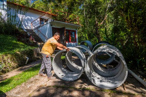 Pedreiro com manilhas de concreto para construção de fossa séptica residencial