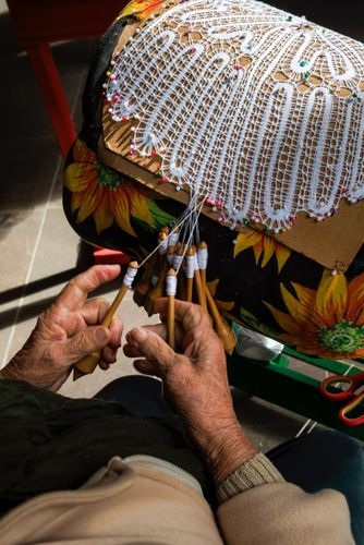 Mãos de rendeira produzindo renda de bilro 